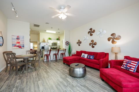 Unwind in your spacious open living area where vibrant red sofas and nautical touches create the perfect coastal retreat.