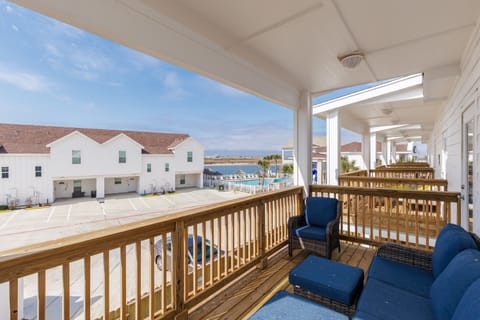 Relax on your private covered balcony with comfortable seating while enjoying views of the resort pool and coastal scenery beyond.