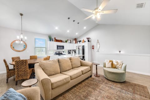 Relax in your bright open-plan living space with cozy seating, including a sleeper sofa, fully equipped kitchen, and soaring ceilings perfect for unwinding.