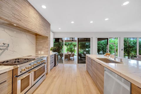 The gourmet kitchen opens on the living room featuring incredible views of the tropical landscape.