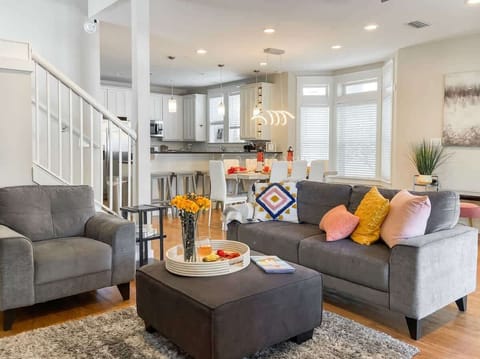 [First Floor] Modern living room with seating for 8-10 people and 60-inch smart TV.