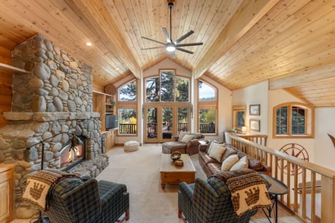 Spacious great room with vaulted ceilings and river rock surrounded wood stove