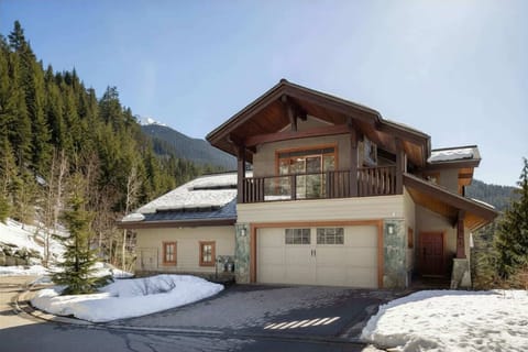- Chalet exterior surrounded by snow-covered pines and scenic mountain views  
- Spacious driveway and private garage offer easy access for guests  
- Minutes from Creekside gondola and Whistler ski village attractions  
