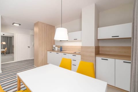 Another angle of the dining and kitchen space, showcasing modern white cabinetry and sleek wooden accents.
