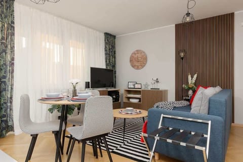 Living room with a fold-out corner sofa, coffee table, TV, closets, exit to balcony and dining area