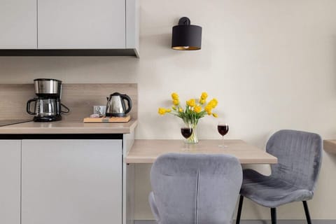 Compact kitchenette with coffee maker, dining area, and yellow floral accents.
