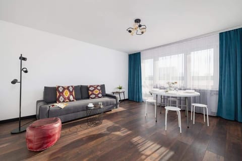 Bright living room with sofa, coffee table, and blue curtains on dark wooden flooring.
