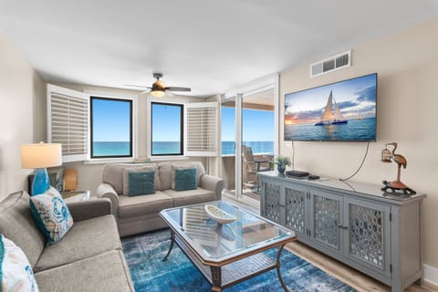 Relax in this bright oceanfront living space where coastal artwork and blue accents complement stunning sea views through your windows.