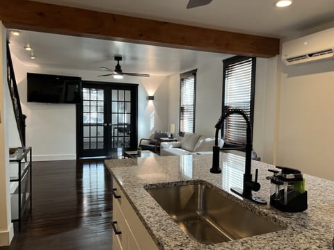 Modern open concept kitchen, living room, and office with double French doors.