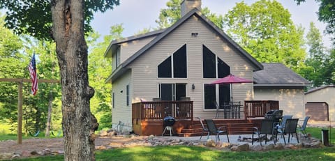 Patio with firepit with a swing set off to the side. Firewood is provided.