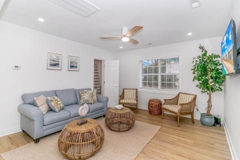 Modern living area with sofa, smart TV, ceiling fan and natural light comfortable space for lounging
