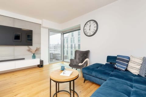 Bright living room with a deep blue sofa, modern decor, and a round coffee table.
