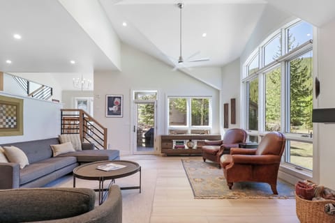 Picture yourself unwinding in this bright, airy living space with soaring vaulted ceilings and natural light pouring in from the floor-to-ceiling windows overlooking the lush trees outside.