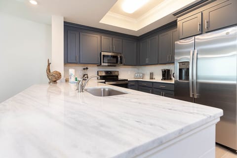 Brew your morning coffee at the marbled counter in this stylish kitchen with elegant cabinetry