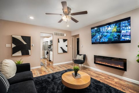 A welcoming living room with a flat screen TV, artwork, and electric fireplace