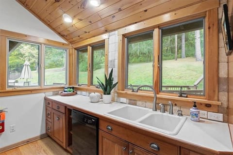 Wash up with a view in this kitchen's clean-up area, framed by panoramic windows that invite the calm of the surrounding woods right into your home.