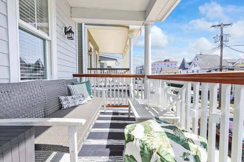 Master Bedroom Balcony-Enjoy a moment of relaxation on the inviting covered porch, featuring comfortable wicker seating perfect for unwinding in the fresh air. The space is bright and sunny, offering a glimpse of the charming neighborhood street.