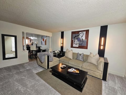 Living Room: Sink into comfort on the modern tan couch, a centerpiece of relaxation. A masterpiece of artwork graces the wall behind the couch, adding depth and character.