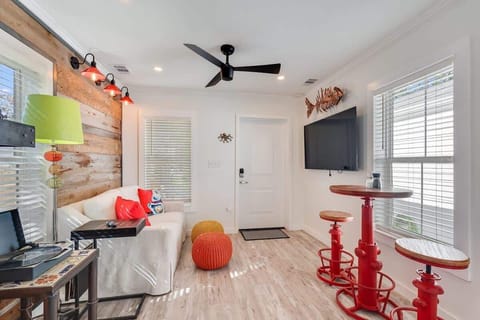 - Bright interior with quirky, colorful accents including red bar stools & vibrant pillows - Cozy space with unique details like a TV, fish decor & dining set for casual meals - Modern fixtures create a welcoming environment for relaxing or entertain