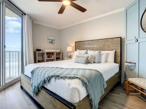 Inviting bedroom featuring a rustic wood bed, soft linens, and balcony access for ocean views.