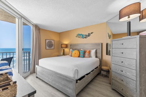 Inviting bedroom with vibrant decor, soft lighting, and stunning balcony access overlooking the ocean.