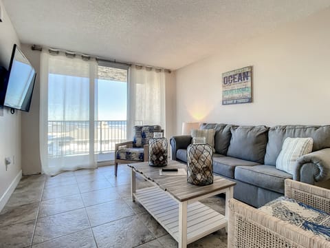 Relax in the comfortable living area, featuring soft seating and ocean views through floor-to-ceiling windows.