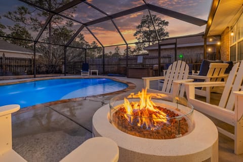 Polywood adirondack chairs around gas fire pit near private heated and screened-in pool.
