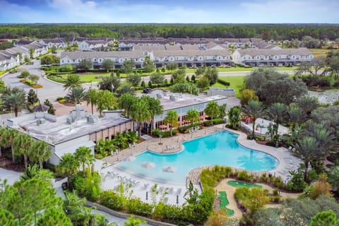 Aerial view of the resort-style community w/ a sparkling pool & lush green surroundings.

