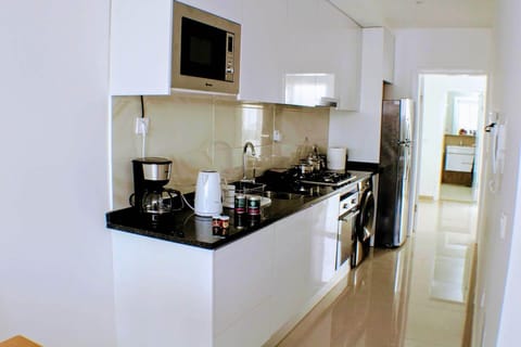 Full kitchen with gas stove and oven, refrigerator, pots, pans, dinnerware