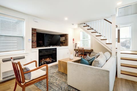 First floor of with an electric fireplace and workspace under stairs