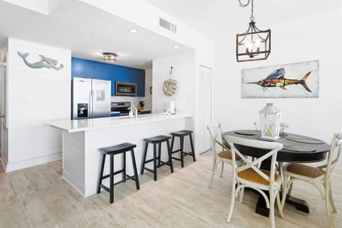 Your coastal-inspired kitchen and dining space features bright blue cabinets, modern appliances, and charming nautical artwork for memorable meals.