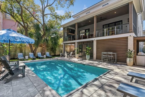 Modern two-story property featuring a private swimming pool surrounded by comfortable lounge chairs and tropical landscaping in a peaceful backyard setting.
