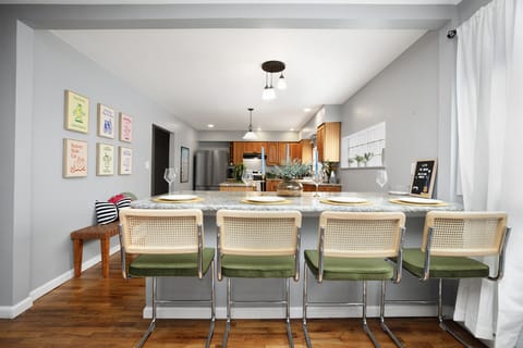 Dining room with playful art and modern kitchen view.