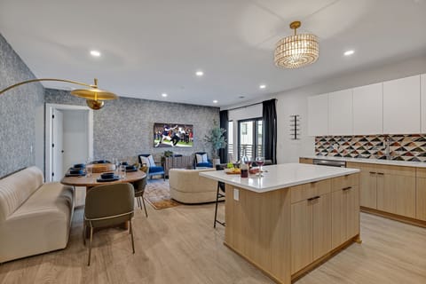 The fully equipped modern kitchen features culinary essentials, stainless steel appliances, and island bar seating.