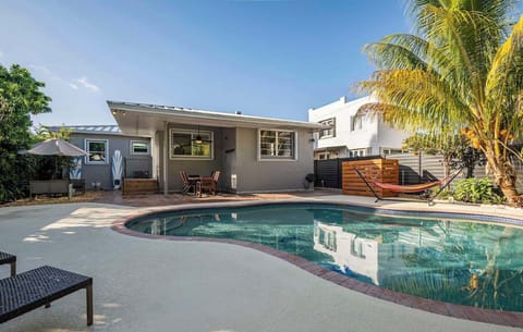 Expansive backyard oasis featuring a pool, abundant outdoor seating, and lush tropical foliage for an authentic island ambiance.