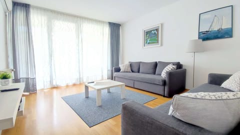 Living room with two sofa beds, armchair, TV, entrance to the terrace and big windows.