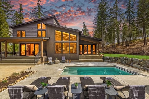 Outdoor Living – Evening Oasis with Illuminated Poolside, Tiered Lounge Seating, and Full-Glass Windows Showcasing Interior Warmth.