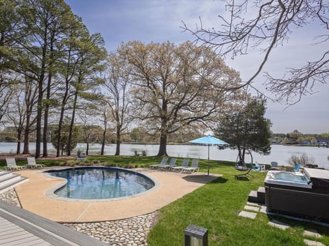 Stunning lakefront pool area with hot tub, loungers, and mature trees creating your private waterside oasis.