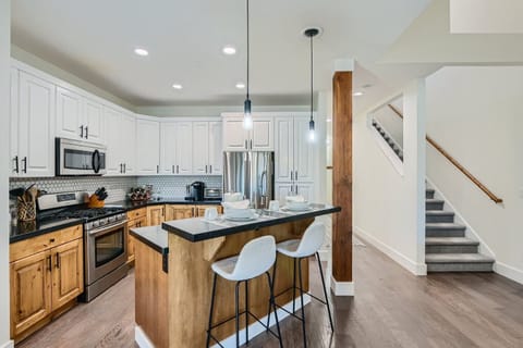 Prepare meals in our fully equipped kitchen, featuring a large island with bar seating, modern stainless steel appliances, and a stylish two-tone design. All the essentials for a great stay.