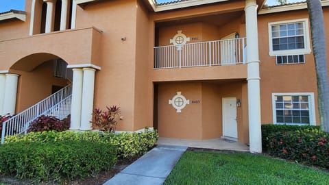 Exterior view of the building with covered entryway, tropical landscaping, and Florida-style architecture.