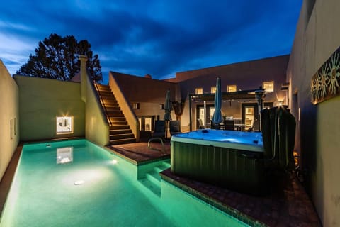 Resort-style backyard at dusk with private pool, spa, and dramatic desert skies