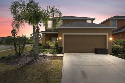 As dusk settles, this charming home showcases warm exterior lighting that highlights the rich earth tones of the siding and inviting landscaping. A spacious driveway leads to a cozy entry, setting the stage for a relaxing stay.
