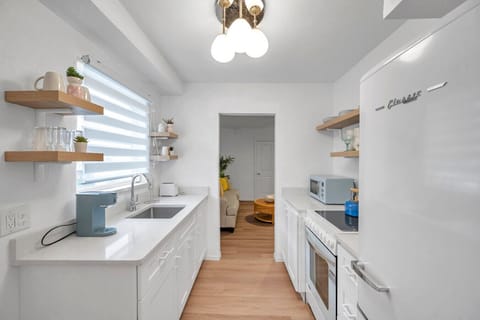Sleek galley kitchen w/ open shelving, modern finishes, and plenty of space to prep meals.