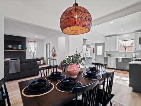 - Open concept kitchen and dining with pendant lighting   - Rustic wooden table set with black dinnerware style   - Seamless flow to living room for easy gatherings  