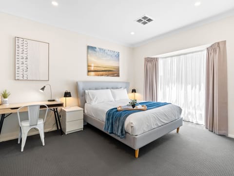 Spacious master bedroom with luxury upholstered queen size bed and work desk space.