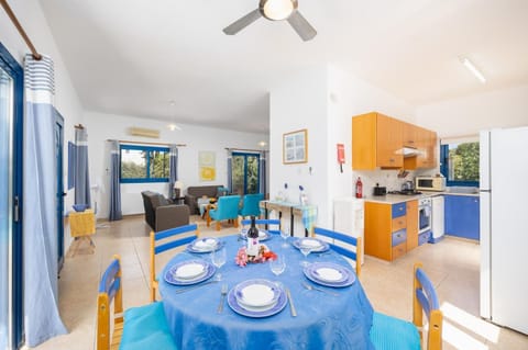 Open-plan living room with sofas, dining area, kitchen, A/C, WiFi internet, and satellite TV