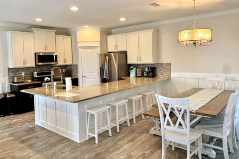 Big, open, well-supplied kitchen with breakfast bar and large dining table.