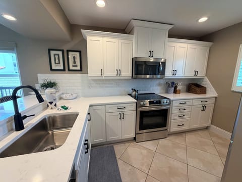 Your fully equipped kitchen features gleaming white cabinetry, modern stainless appliances, and bright countertops—perfect for preparing family meals or morning coffee in your home away from home.