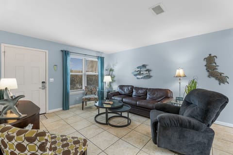 Relax in this cozy living room with leather seating and ocean-themed decor.