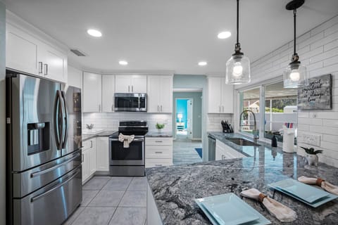 This modern kitchen blends style and function, featuring a spacious layout, bar seating, and plenty of natural light.